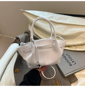 Close-up of white lychee pattern bucket bag featuring wing design and silver metal charm