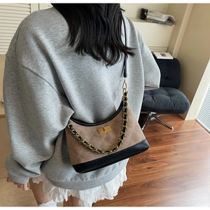Détail d'un sac sous les aisselles en daim matelassé marron avec boucle en métal doré