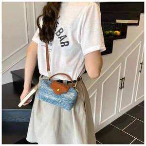 Blue woven denim crossbody bag with brown leather strap worn by a model in a studio