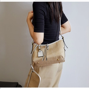 Detailed view of handmade woven straw bag with white leather trim and metal base feet