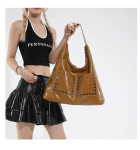 Detail of vintage brown tote bag with glossy finish and stylish silver metal rivets