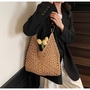 Detail view of woven straw tote bag with round buckle strap and hollow knit texture