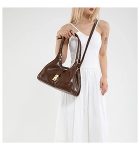 Détail d'un sac porté épaule en cuir marron avec fermoir doré et bandoulières amovibles