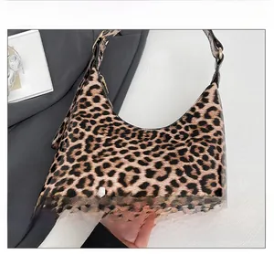 Detail shot of glossy leopard print faux leather texture and adjustable strap on underarm bag