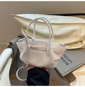Close-up of white lychee leather bucket bag with folded pleats and silver metal charm