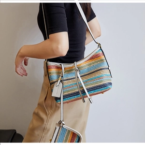 Detail view of colorful striped woven crossbody bag with white leather straps and trim
