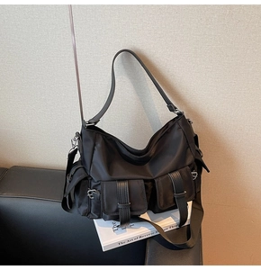 Close-up of black nylon tote bag with functional pockets and silver metal buckles