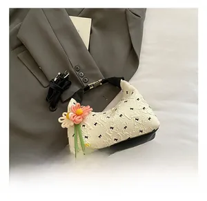 Detail einer beigen Handtasche mit schwarzen Schleifenmustern und bunten Blumen
