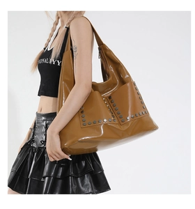 Detail showing shiny brown faux leather tote with two rows of hexagonal metal rivets