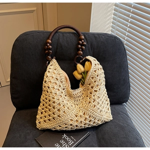 Detailed texture of hand-woven straw tote bag with brown wooden bead handles on a chair