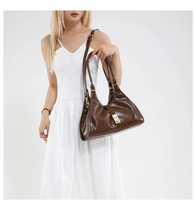 Détail du sac sous les aisselles en cuir marron vintage avec boucle dorée et sangle