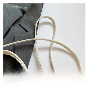 Détail d'un sac à bandoulière en cuir blanc crème avec coutures fines et crochets dorés