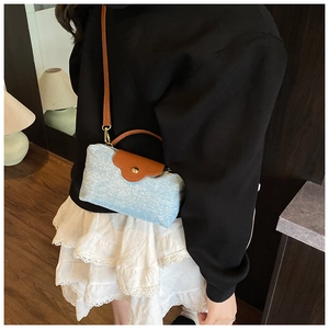 Detail of light blue tweed crossbody bag with brown leather flap and gold hardware