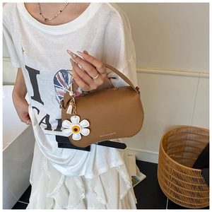 Close-up of caramel lychee leather handbag with daisy pendant and tassel details