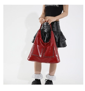 Close-up of glossy red tote bag featuring silver hexagonal rivets and sleek patent finish