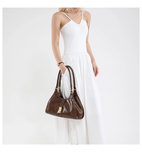 Détail d'un sac à main en cuir marron foncé avec fermoir doré sur fond blanc