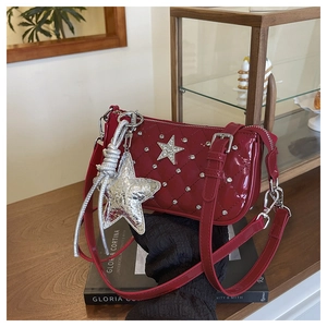 Detail of red quilted patent leather shoulder bag with silver star studs and charms