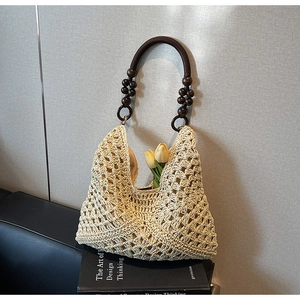 Close-up of woven tote bag with brown beaded handle and decorative yellow tulips