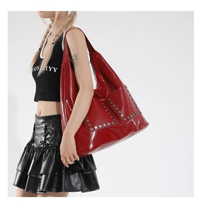 Detail of red tote bag featuring silver hexagonal rivets and glossy finish with model
