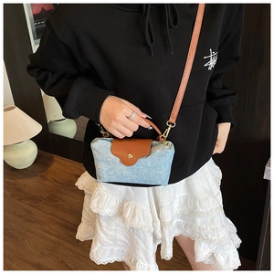 Close-up of blue denim mini crossbody bag with brown leather flap and golden buckle