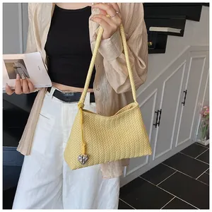 Detail of light yellow woven hobo bag featuring a silver heart charm and textured pattern