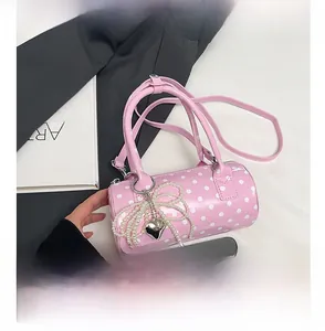 Détail du sac cylindrique rose à pois avec nœud en perles et référence de taille