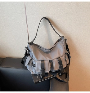 Detail of grey multi-pocket nylon tote bag with functional buckled flaps and side zipper