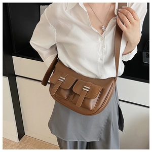Brown leather crossbody bag detail featuring two pockets with silver metal buckles and strap