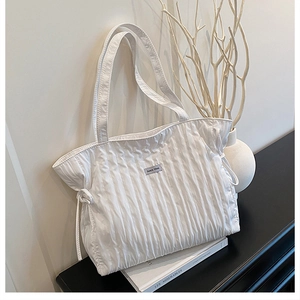 Dettaglio borsa tote bianca a pieghe con coulisse laterale e logo del marchio minimalista