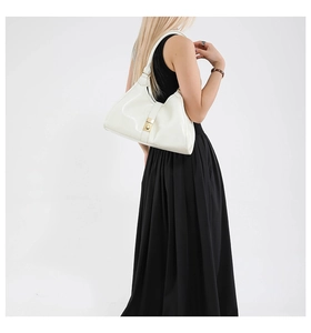 Détail du sac à épaule en cuir verni blanc avec boucle métallique dorée porté par mannequin