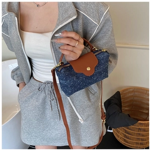 Detailed view of polka dot denim crossbody bag with brown leather strap and gold hardware