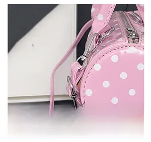 Détails des crochets en métal argenté et du zip sur le sac cylindrique rose à pois