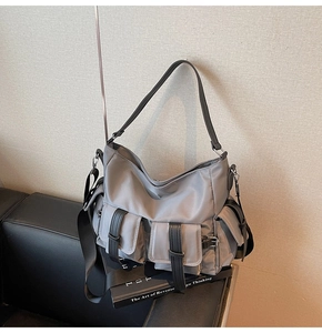 Close-up of grey nylon tote bag showing multiple buckled pockets and metal hardware