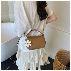 Brown lychee texture bag with daisy charm and adjustable strap shown on a model