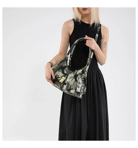 Détail du motif camouflage et de la boucle en métal doré sur le sac à bandoulière en toile