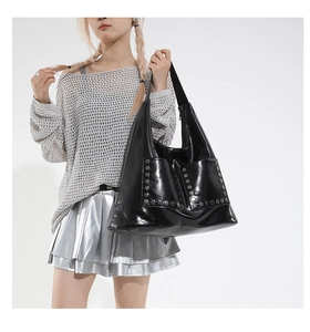 Close-up of black glossy tote bag with metal rivets and spacious pockets detail