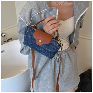 Detail of blue denim and brown leather small crossbody bag with gold hardware in casual setting