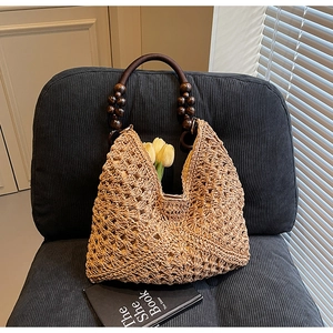 Close-up of a woven straw tote with beaded wood handles and rustic knit texture