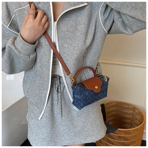 Polka dot denim mini crossbody bag with brown leather handles worn by a fashion model