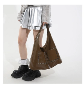 Detail of vintage brown leather tote bag featuring large front pockets and silver studs