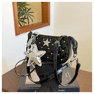 Close-up of black patent leather crossbody bag with quilted stars and silver rhinestone charms