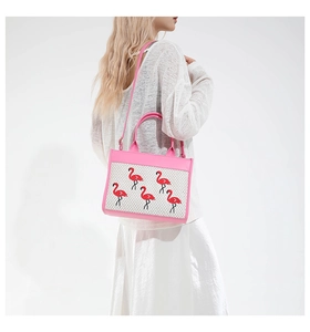Détail du sac à main rose et beige avec des motifs de flamants roses brodés en rouge