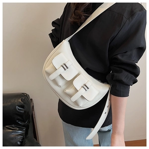 Detail of white crescent crossbody bag with double front pockets and silver buckles