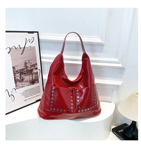 Detail of red hobo bag with glossy finish and silver hexagonal metallic studs decor