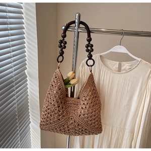 Detail of woven straw tote bag featuring beaded wooden handles and hollow texture