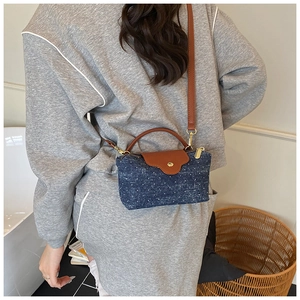 Detail of polka dot denim shoulder bag with brown leather handles worn by a model