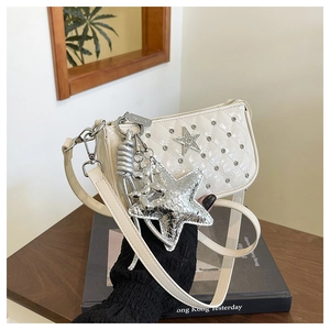 Detail of beige quilted crossbody bag with silver studs and star shaped charm accessory