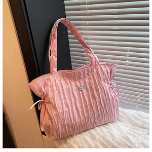 Dettaglio della borsa tote rosa a pieghe con nodi a coulisse ed etichetta laterale