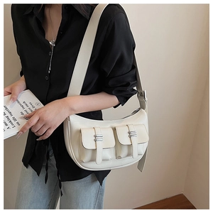Detail of cream leather crescent bag with dual utility pockets and silver metal buckles