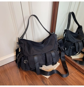 Detail view of high-density nylon tote bag with utility pockets and metal buckles on wood floor